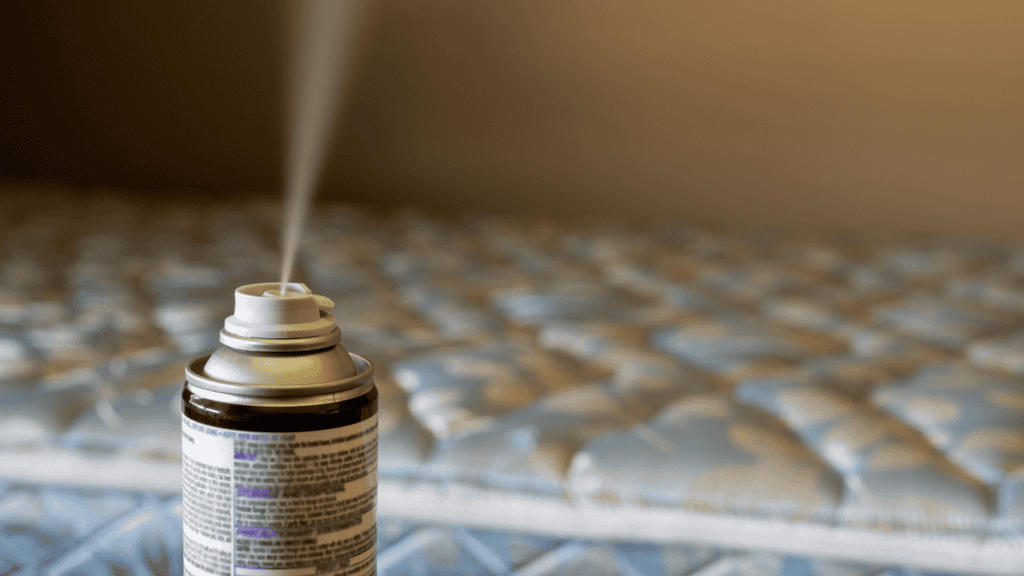 "Close-up of an aerosol bed bug spray releasing mist, with a mattress in the background, highlighting a common DIY method for treating bed bug infestations."